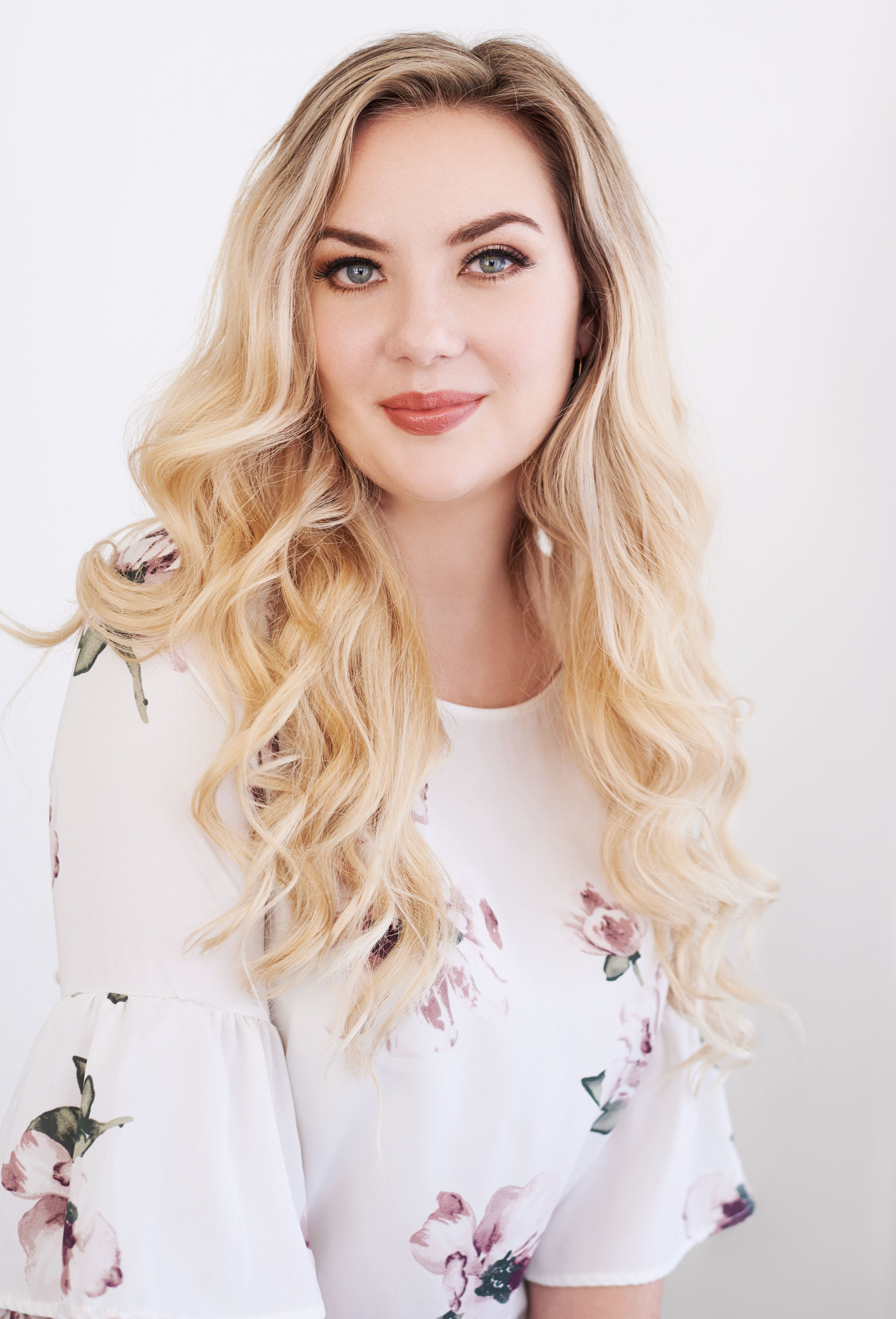 Beautiful smiling white woman with long blonde hair wearing a white blouse. Professional headshot and glamour shot.