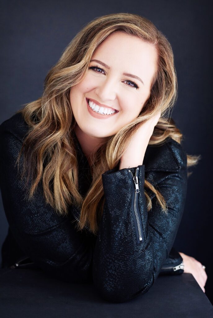 Beautiful smiling white woman with long blonde hair wearing a black jacket. Professional headshot and glamour shot.