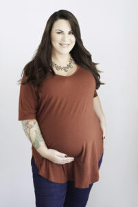 Beautiful pregnant smiling brunette woman with tattoos wearing a red shirt