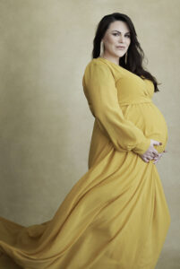 Beautiful smiling brunette pregnant woman in long yellow dress