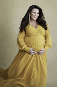 Beautiful smiling pregnant brunette woman in long yellow dress