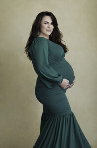 Beautiful pregnant brunette woman in long green dress